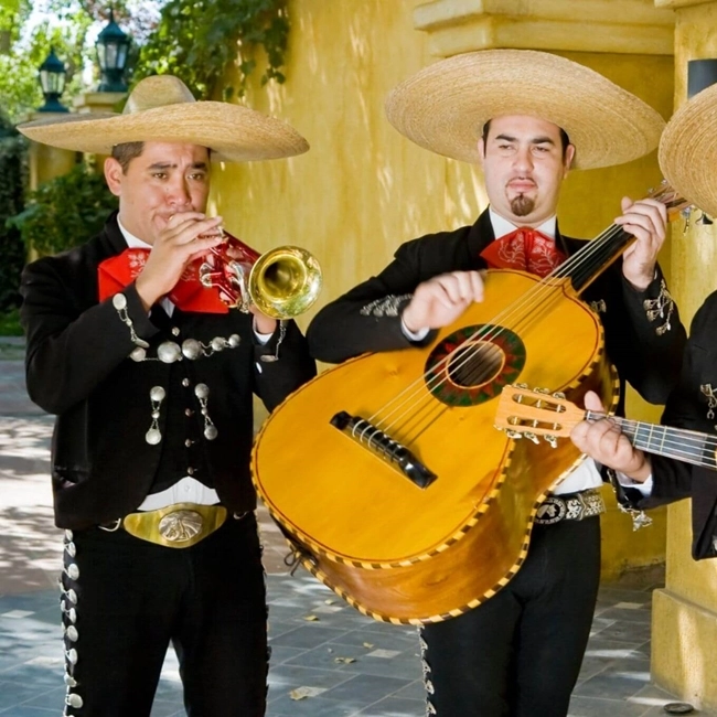 Tres hombres con trajes mexicanos tocan instrumentos musicales, mostrando la riqueza de la cultura y la música tradicional.