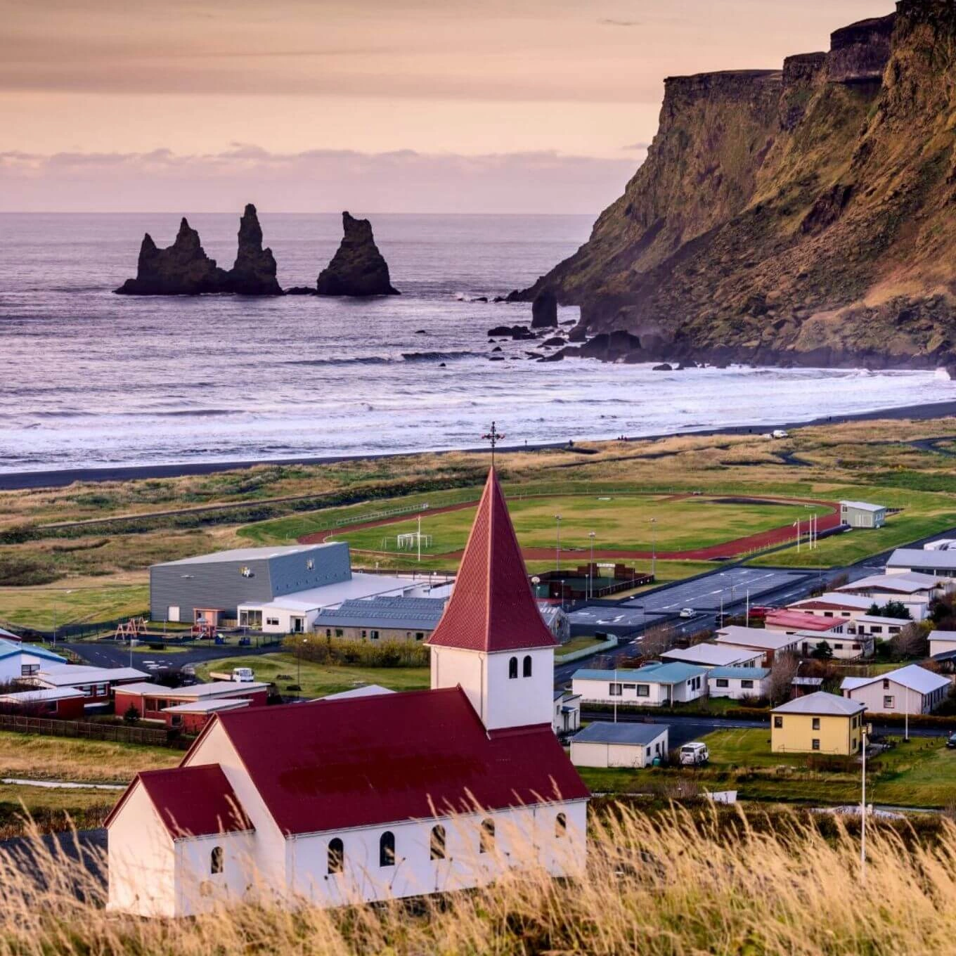 Una iglesia encaramada a una colina en Islandia, con una vista panorámica del océano.