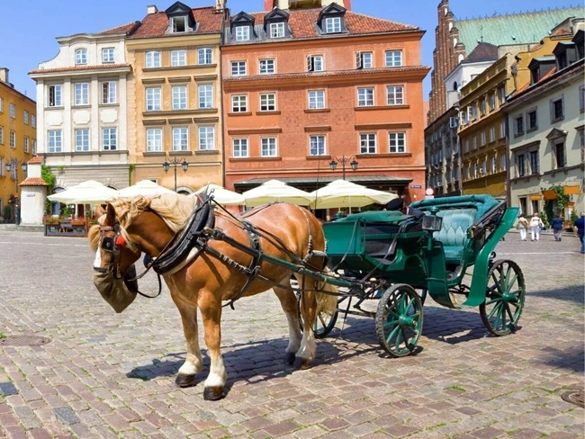 Un coche de caballos recorre las históricas calles de Varsovia, Polonia, mostrando el encanto del casco antiguo.