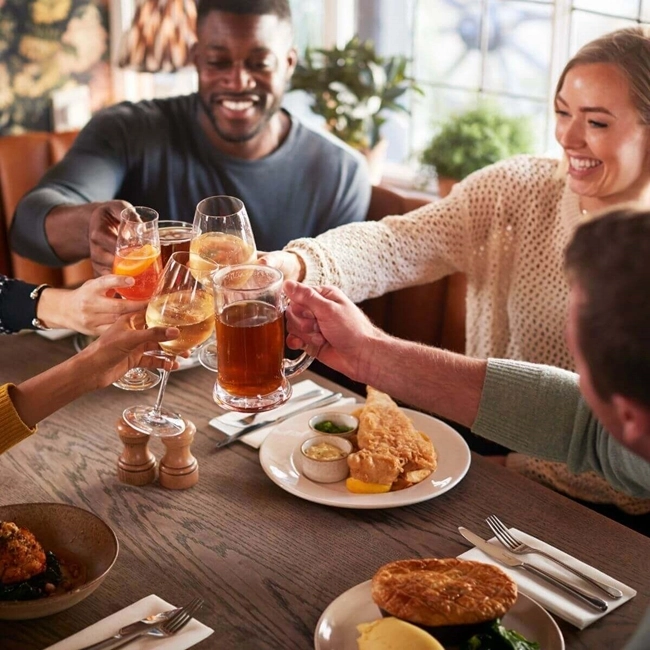 Un grupo de personas brindando alegremente alrededor de una mesa en un restaurante, celebrando juntos en un ambiente festivo.