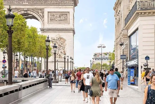 Un grupo de personas pasea por una acera adyacente al Arco del Triunfo, mostrando el vibrante ambiente parisino.