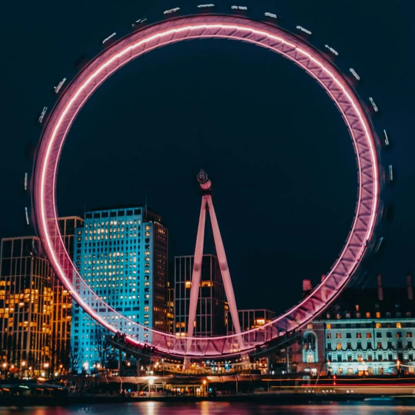 La noria London Eye iluminada por la noche, destacando su estructura en un cielo oscuro y estrellado.