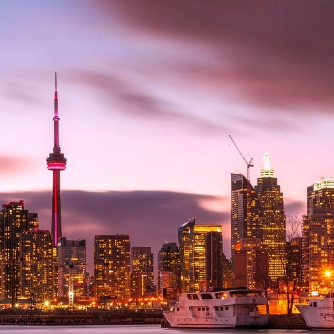 El horizonte de Toronto iluminado al atardecer, mostrando una mezcla de arquitectura moderna y belleza natural contra un cielo crepuscular.