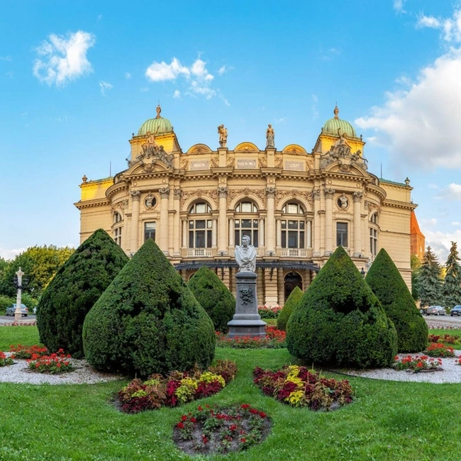 Un impresionante edificio se alza majestuoso frente a un exuberante parque verde, exhibiendo belleza arquitectónica y serenidad natural.